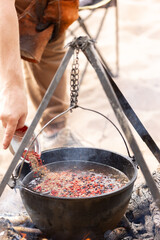 Cooking at the campsite, adding a spice mixture to the cauldron