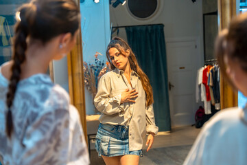 Customer choosing clothes in clothing store dressing room mirror