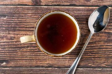 Hot consomme beef tail served in ceramic cup on rustic wooden table