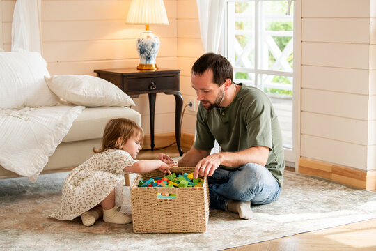 Father and little girl playing with colorful wooden building block