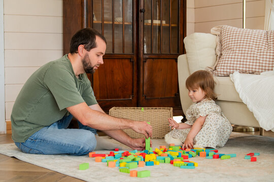 Father and little girl playing with colorful wooden building block