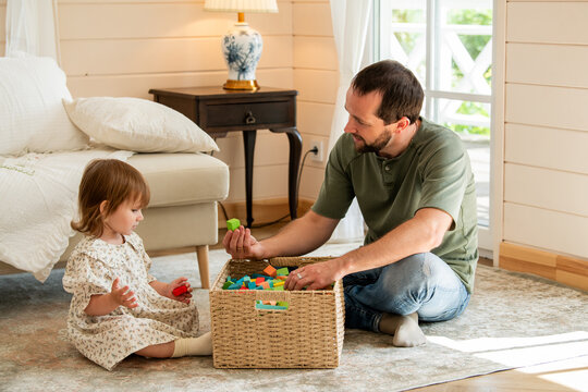 Father and little girl playing with colorful wooden building block