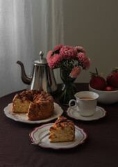 A piece of apple pie, a cup of coffee, a bouquet of flowers on a table with a brown tablecloth