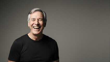 Fototapeta premium Smiling senior man: An portrait of a cheerful, older man in a black t-shirt, captured in a studio setting with a soft focus. His genuine smile radiates warmth and happiness.