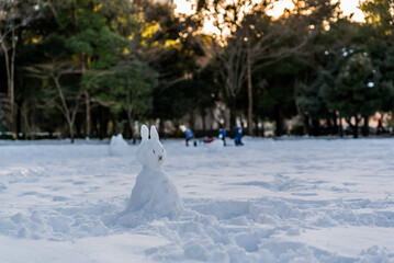 公園に雪が積もった日に作られたウサギっぽい雪だるまと夕暮れ