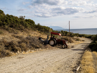 Tractor with wood chipper, red agricultural tractor equipped with a wood chipper machine, processing branches and logs into wood chips. Concept of farming, forestry, agriculture, and rural work.