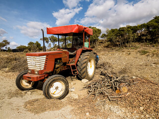 Tractor with wood chipper, red agricultural tractor equipped with a wood chipper machine, processing branches and logs into wood chips. Concept of farming, forestry, agriculture, and rural work.