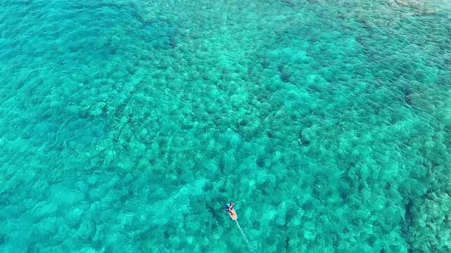 Aerial view of the clear turquoise water, with a paddleboarder, showcasing a blend of light and dark tones in the ocean's depths, Hawi, Hawaii, United States.