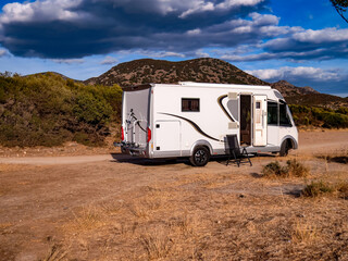 Camper van by the sea, a white camper van parked near the seaside under a clear blue sky. Concept of travel, vacation, freedom, and outdoor camping lifestyle.