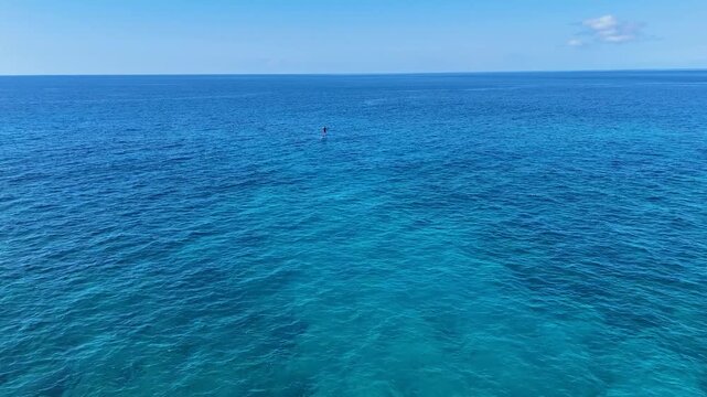 Aerial view of a lone paddle boarder gliding across the tranquil, turquoise expanse of the ocean, a serene scene of solitude and adventure, Hawi, Hawaii, United States.