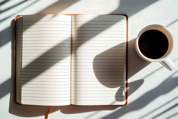 Top-down view of an open lined notebook with a cup of black coffee and pencils on a wooden desk, illuminated by warm morning sunlight that casts soft shadows