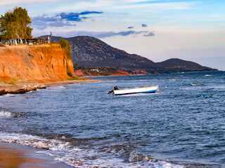 Boat and sea cliff, small boat floating on calm sea near a rocky cliff. Scenic view of the Mediterranean coastline and natural landscape.