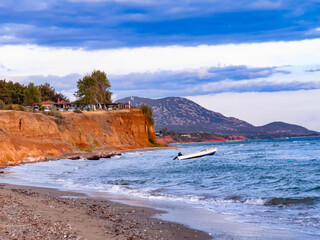 Boat and sea cliff, small boat floating on calm sea near a rocky cliff. Scenic view of the Mediterranean coastline and natural landscape.