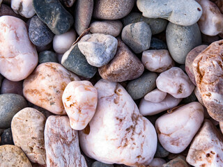 Sea stones / Pebbles on the beach, close-up of sea stones and pebbles on the beach, naturally shaped by the waves. Concept of background, texture, and natural detail.