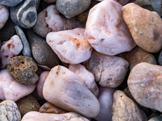 Sea stones / Pebbles on the beach, close-up of sea stones and pebbles on the beach, naturally shaped by the waves. Concept of background, texture, and natural detail.