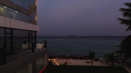 Aerial view of a building with a jacuzzi near the ocean with lights at dusk, creating a serene and luxurious ambiance, Kamadhoo, Baa Atoll, Maldives.