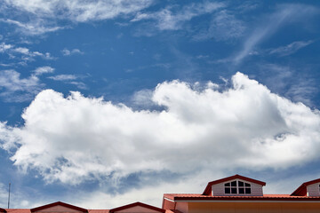 Fluffy clouds with blue sky over the roof top	
