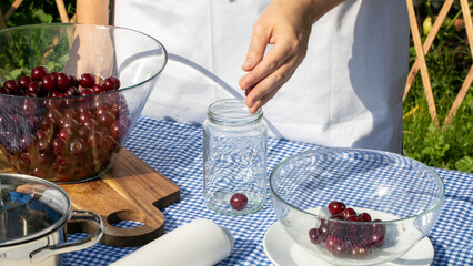 A Caucasian male gently places vibrant cherries into a jar, evoking Cherry Blossom Festival...