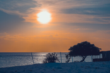Floating in the waves at sunset, sun just above horizon, going down, orange sky, tranquil sea. Peaceful moment, vacations, summer mood. Dominican Republic. Horizontal video.