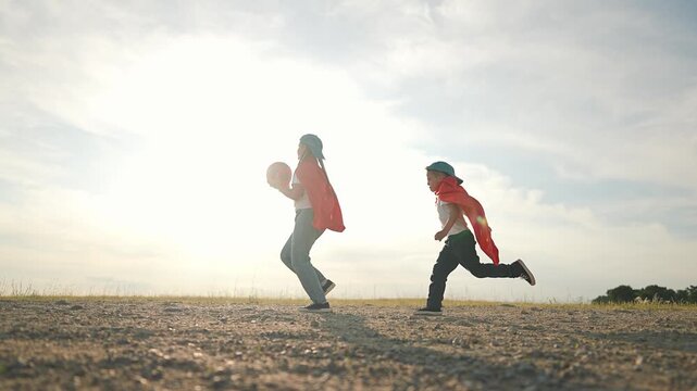 Boy runs after sister ball. Girl playing game outdoors. Child in field having fun. Kid enjoys running fast. Brother and sister in play. Girl leads game, boy follows in exciting ball chase outdoors.