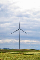 Lone turbine dances under brooding skies, capturing whispers of Gaia, perfect for Global Wind Day or Earth Hour celebration