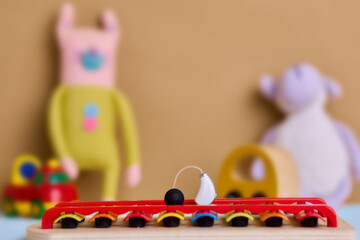 White hearing aid for kids rests on a xylophone, surrounded by fun toys to inspire auditory play. Children's audiology