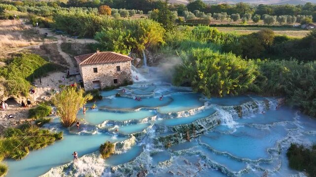 Aerial view of the Saturnia hot springs cascading down the landscape, creating a stunning contrast of turquoise pools and lush greenery, Saturnia, Toscana, Italy.