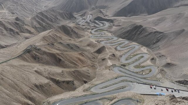 Aerial view of the winding Panlong Ancient Road slicing through the arid, mountainous terrain, creating a stark contrast, Panlong Ancient Road, China.