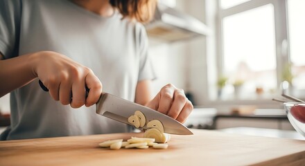 Woman expertly slices garlic on a wooden board in a modern kitchen