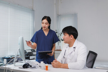 Medical professionals discussing patient data on computer in hospital room