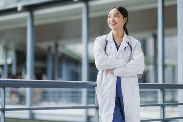 Smiling doctor leaning on railing outside hospital