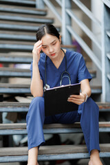 Fototapeta premium Stressed young doctor reading medical report on stairs