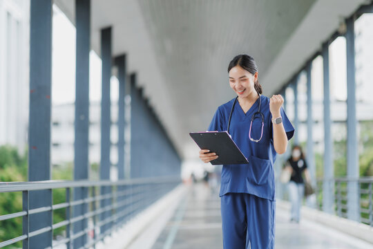 Happy doctor celebrating success reading medical report in hospital corridor - Powered by Adobe