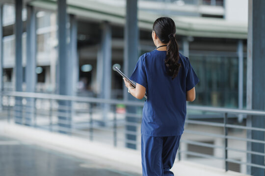 Nurse walking in hospital corridor holding tablet