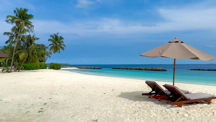 Tropical white sandy beaches, turquoise sea, palm trees and sun loungers under umbrellas