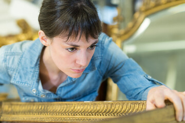 woman inspecting antique mirror frame design