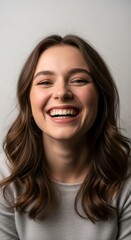 Naklejka premium Portrait of a woman with brown hair smiling widely showing teeth against a white background