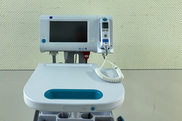 A sleek medical monitoring device sits on a clean surface, displaying information for patient care. It features a screen, buttons, and a coiled cord, ready for use in a clinical environment.