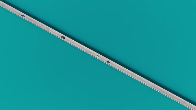 Aerial view of cars traversing a straight bridge cutting through the aquamarine waters of Baisha Lake, Baisha Lake, China.