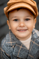 close-up portrait of a boy in the fall in a park, a small child in a brown coat on the street among yellow leaves