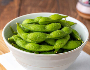 A close-up shot of a bowl filled with fresh, green edamame pods, ready to eat.
