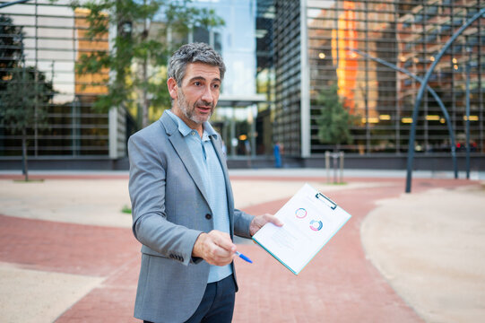Mature man presenting business data with charts outdoors