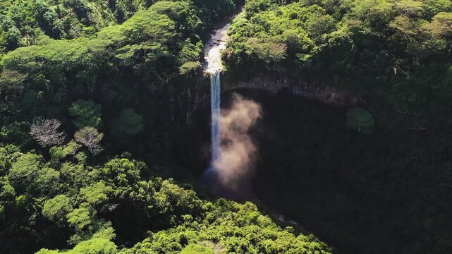 Aerial view of Chamarel Waterfall cascading down a cliff amidst lush greenery, creating a misty spectacle in the heart of the landscape, Chamarel, Rivi&egrave;re Noire District, Mauritius.