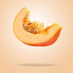 Slice of ripe pumpkin in air against dark beige background