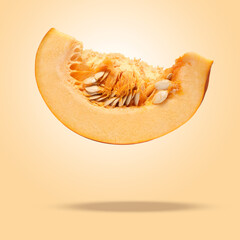 Slice of ripe pumpkin in air against dark beige background
