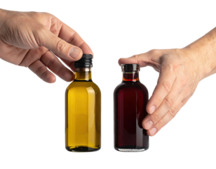 Two small glass bottles with dark caps, held by hands against a black background