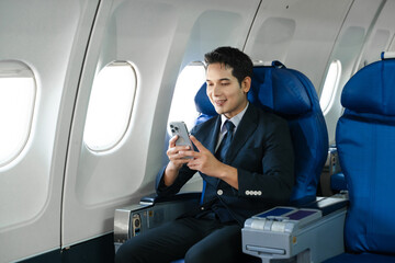 Young Asian executive excels in first class, multitasking with digital tablet, laptop and smartphone. Travel in style, work with grace.