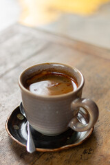 Freshly brewed espresso coffee in a ceramic cup with saucer on rustic wooden table, warm and cozy atmosphere.