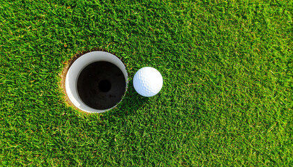 Golf ball hole green grass putting closeup outdoor sport competition leisure precision sunlight shadow summer recreation field texture round white success target accuracy equipment game relaxation