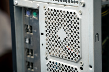 Obraz premium Back side of an old dusty computer system unit with visible USB ports and cooling fan covered in dust, obsolete PC hardware, dirty desktop tower 